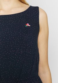Abito senza maniche blu navy con pois rosa, dotato di un dettaglio di ricamo floreale sul petto e una vita elastica per definire la silhouette.
