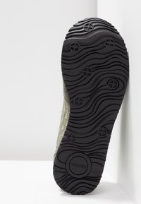 Semelle en caoutchouc noire avec motif ondulé et grips circulaires, comportant le nom de la marque « WODEN » au niveau du talon.