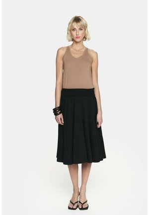 Brązowy bezrękawnik w połączeniu z czarną, plisowaną spódnicą midi o gładkiej fakturze i szerokim pasie. Czarne akcesoria dopełniają całość.