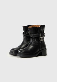 Bottes noires en cuir à chevilles avec un design à l'aspect froissé, doublure tan contrastante, détail de boucle et un talon empilé pour une hauteur supplémentaire.