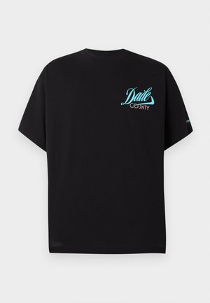 Must lühikeste varrukatega T-särk, millel on vasakul rinnal sinise ja roosa värviga kiri "Dade County", valgel taustal.