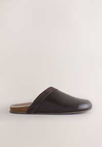 Chausson en cuir marron à enfiler avec un parement en daim et une semelle intérieure en liège moulé, semelle plate et bout fermé arrondi.