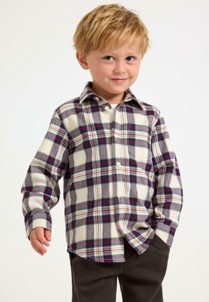 Gekraagde gekorrelde blouse met rood, blauw en crèmekleurige ruitpatronen. Heeft lange mouwen en een kraag. Gecombineerd met donkergrijze broek.