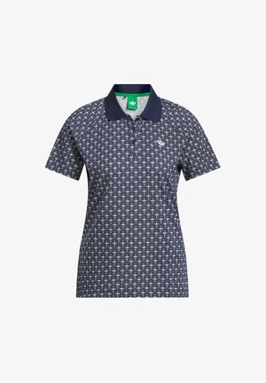 Navy plava polo majica s ponavljajućim bijelim geometrijskim uzorkom, tamnim ovratnikom i malim zeleno-bijelim troklapnim logotipom na lijevoj strani prsa.