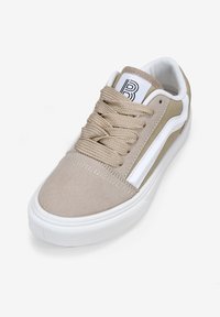 Zapatillas beige con parte superior de ante, suela de goma blanca y una franja lateral en contraste. Cuenta con cordones redondos y un cuello acolchado.