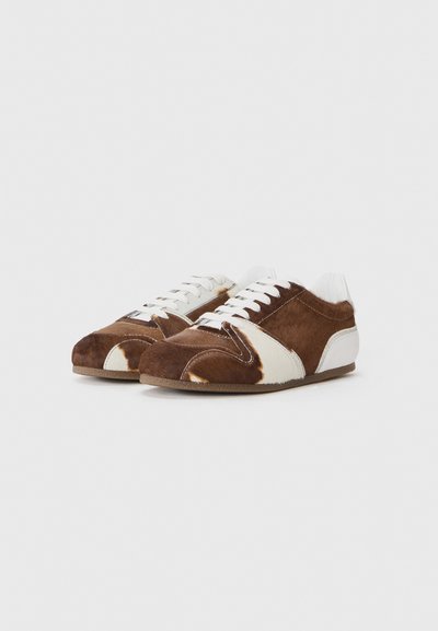 Sneaker marroni e bianchi con motivo, realizzati in suede e pelle, dotati di lacci bianchi e con un design a profilo basso, punta arrotondata e bordi morbidi.
