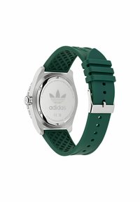 Boîtier de montre en acier inoxydable argenté et bracelet en caoutchouc vert avec un design texturé ; possède un logo gravé au dos.