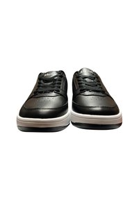 Un paio di sneaker in pelle nera con lacci neri e suole bianche, viste frontalmente su uno sfondo bianco.