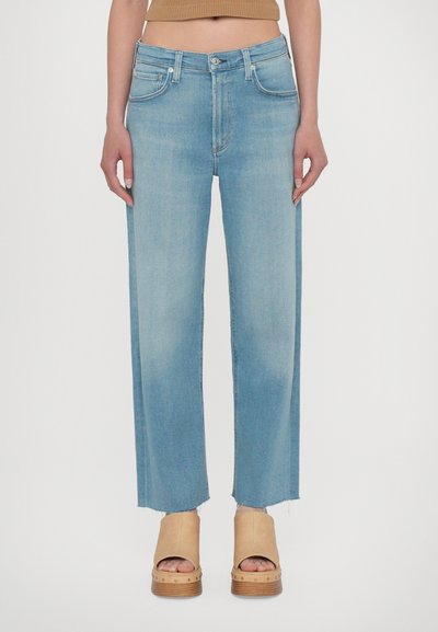 Világoskék, bő szárú farmernadrág nyers szegéllyel, denim anyagból készült. Öt zsebbel, gombos záródással és finom kopással a textúra érdekében.