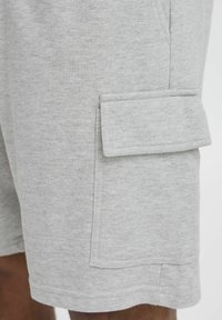 Graue Baumwollshorts mit einer seitlichen Cargo-Tasche, elastischem Bund und glatter Textur. Genähte Säume und lässiges Design.