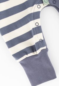 Gestreifter Babyschlafanzug in Marineblau und Creme mit Druckknopfverschlüssen und gerippten Bündchen. Weicher Baumwollstoff mit einem bequemen Sitz.