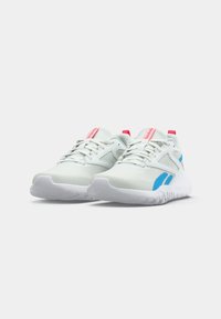 Un paio di scarpe da atletica bianche con accenti blu, suole bianche e linguette rosse, mostrate da un'angolazione bassa frontale su uno sfondo bianco.