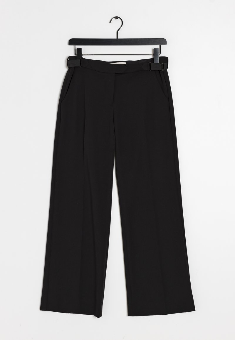 Svarta vida byxor med veck, platt midjeband och sidfickor, hängande på en svart galge mot en vit bakgrund.