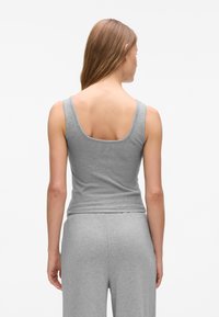 Top grigio senza maniche con schiena a barca, realizzato in tessuto morbido e elasticizzato. Il design è aderente in vita e presenta una texture liscia.