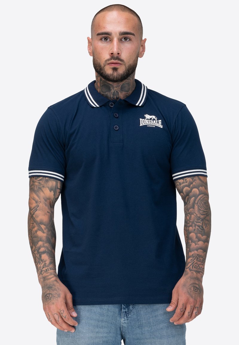 Dunkelblaues Polohemd mit weißen Streifen am Kragen und an den Ärmeln. Verfügt über drei Knöpfe und ein Lonsdale-Logo auf der linken Brust. Weicher Stoff.