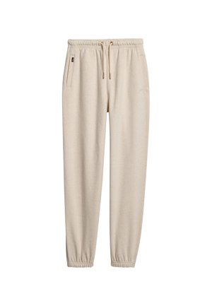 Pantaloni jogger beige realizzati in un tessuto morbido, con vita elasticizzata e cordino, e polsini elastici alle caviglie. Una tasca laterale visibile.
