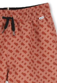 Shorts de bain de couleur rouille avec un motif géométrique. Dotés d'une taille élastique avec cordon de serrage et d'une petite étiquette de logo. Texture lisse.