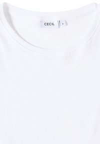 Bílý žebrovaný tričko s kulatým výstřihem a štítkem "CECIL" poblíž límce. Tkanina vypadá měkce a elasticky. Velikostní štítek označen "S".