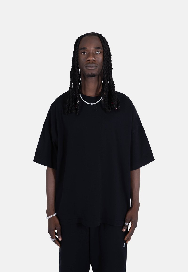 Svart oversized t-skjorte i myk stoff med korte ermer. Har rund hals, minimal merking og er kombinert med svarte bukser.