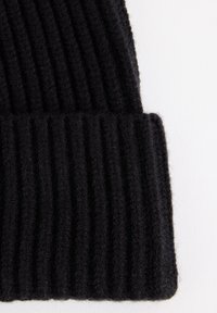 Mustan neulepipo, jossa on pystysuora ribbikuvio ja käänteinen hiha. Valmistettu pehmeästä materiaalista, joka tarjoaa lämpöä ja mukavuutta.