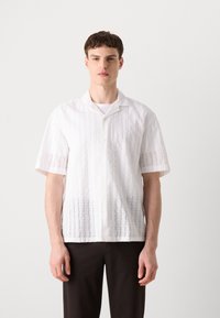 Kortere mouwen, witte, knoopsluiting blouse met een gestructureerd patroon en subtiele verticale strepen. Gemaakt van lichte, ademende stof.