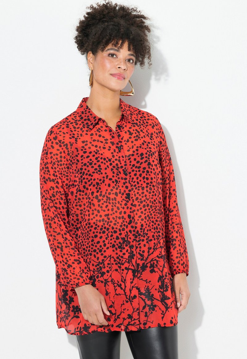 Blusa roja con estampado de puntos negros, con botones en el frente, cuello y mangas largas. El diseño incluye acentos florales en el dobladillo.