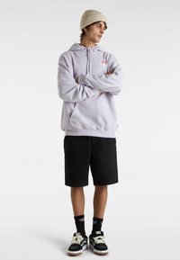 Light purple hooded sweatshirt with front pocket, black shorts, and black and white sneakers with brown sole. White knit beanie accessory.