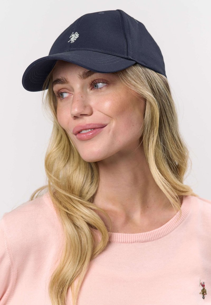 Șapcă de baseball bleumarin cu formă structurată și bor curb, având un mic emblem brodat pe partea din față.