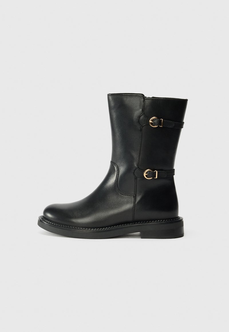 Black leather ankle boot with a rounded toe, decorative gold buckles on the sides, and a textured sole. Smooth finish and mid-height shaft.