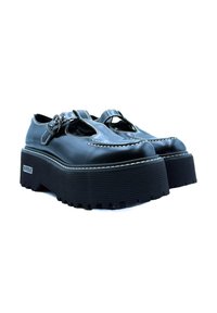 Scarpe platform in pelle nera con design a taglio, cuciture decorative e cinturino con fibbia. Suola in gomma spessa con superficie testurizzata.