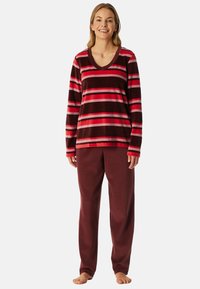 Top de manga larga a rayas rojas y marrones con escote en V, combinado con pantalones burdeos lisos, ambos en un tejido suave parecido al forro polar.