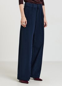 Pantaloni a gamba larga in velluto a coste blu navy con righe verticali, caratterizzati da una vita alta e una chiusura con bottoni. Texture liscia e vestibilità sartoriale.