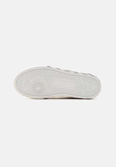 Semelle blanche de basket avec motifs en chevrons et motifs circulaires sur un fond clair uni.