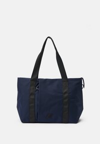 Sac fourre-tout marine en tissu durable, avec des poignées noires, un accent de logo et un design rectangulaire spacieux pour un usage polyvalent.