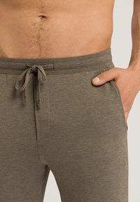 Grå drawstring sweatpants med en slät textur, elastisk midja och sidofickor, uppvisade mot en neutral bakgrund.