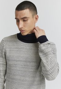 Strickpullover mit einem gerippten marinefarbenen Kragen und einem strukturierten Muster aus abwechselnden marine- und cremefarbenen Streifen. Lange Ärmel mit enganliegenden Bündchen.