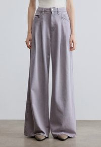 Ανοιχτό μωβ τζιν παντελόνι με φαρδύ πόδι από τζιν ύφασμα, με ψηλή μέση, εμπρόσθιες τσέπες και κούμπωμα με κουμπί. Μαλακή υφή και άνετη εφαρμογή.
