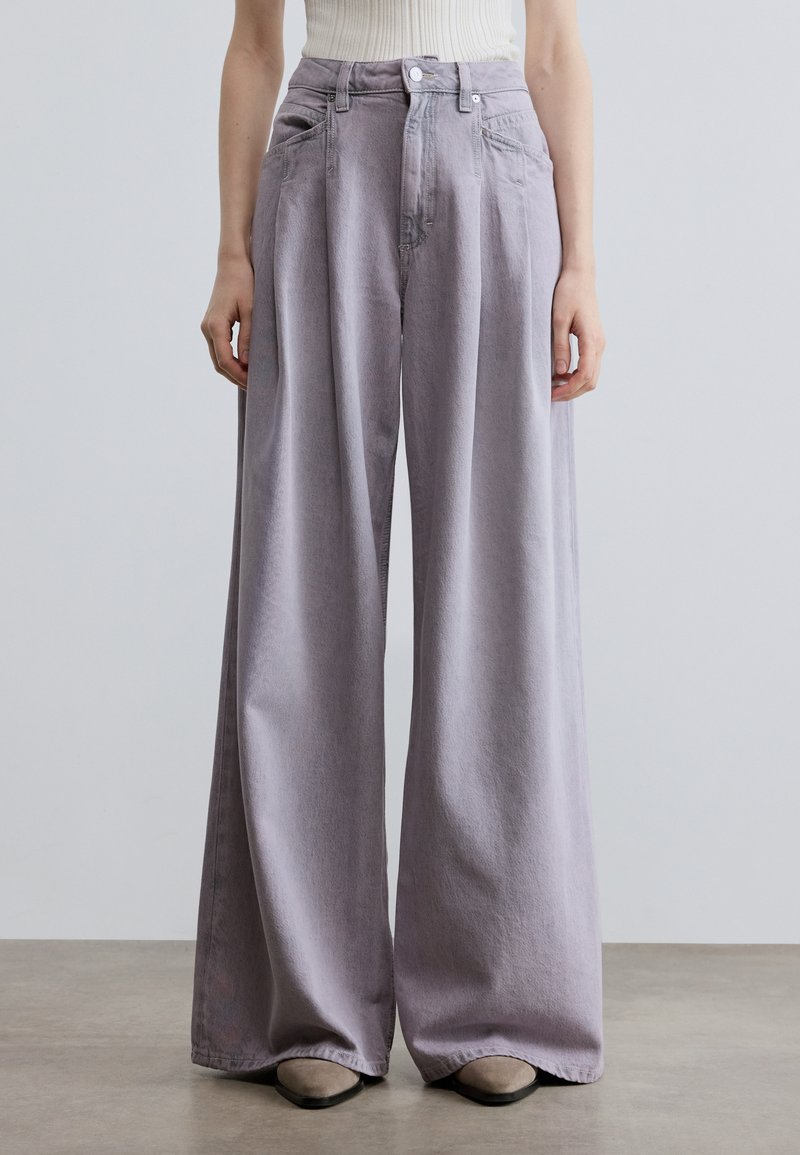 Ανοιχτό μωβ τζιν παντελόνι με φαρδύ πόδι από τζιν ύφασμα, με ψηλή μέση, εμπρόσθιες τσέπες και κούμπωμα με κουμπί. Μαλακή υφή και άνετη εφαρμογή.