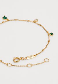 Bracciale in tonalità oro con design a catena collegata, caratterizzato da pietre preziose verdi e trasparenti. Include una chiusura a moschettone e lunghezza regolabile.