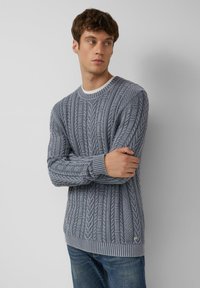 Sweter w kolorze jasnoniebieskim z teksturowanym splotem w warkocz. Posiada ribbowany okrągły dekolt i mankiety oraz mały detal z logo na dole.