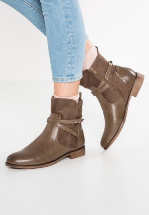 Botas marrones hasta el tobillo con una parte superior de cuero liso y acentos de ante. Presenta un cierre de cremallera lateral, correas decorativas y un tacón bajo de madera.