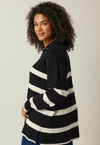 Schwarz-weißer gestreifter Pullover mit Kragen, seitlichen Schlitzen und lockerer Passform, ausgestattet mit einer weichen Textur und Strickstoff.