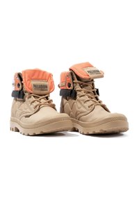 Stivali ankle beige con suola in gomma flessibile, upper in tessuto testurizzato, colletto arancione imbottito, cinturino nero e etichetta con logo sulla linguetta.