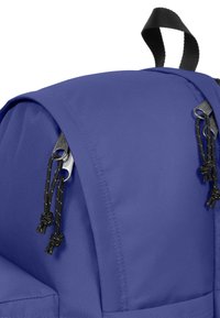 Lila ryggsäck med en slät tygkvalitet och en strukturerad form. Inkluderar svarta dragkedjor och snören för stängning med hållbar söm.