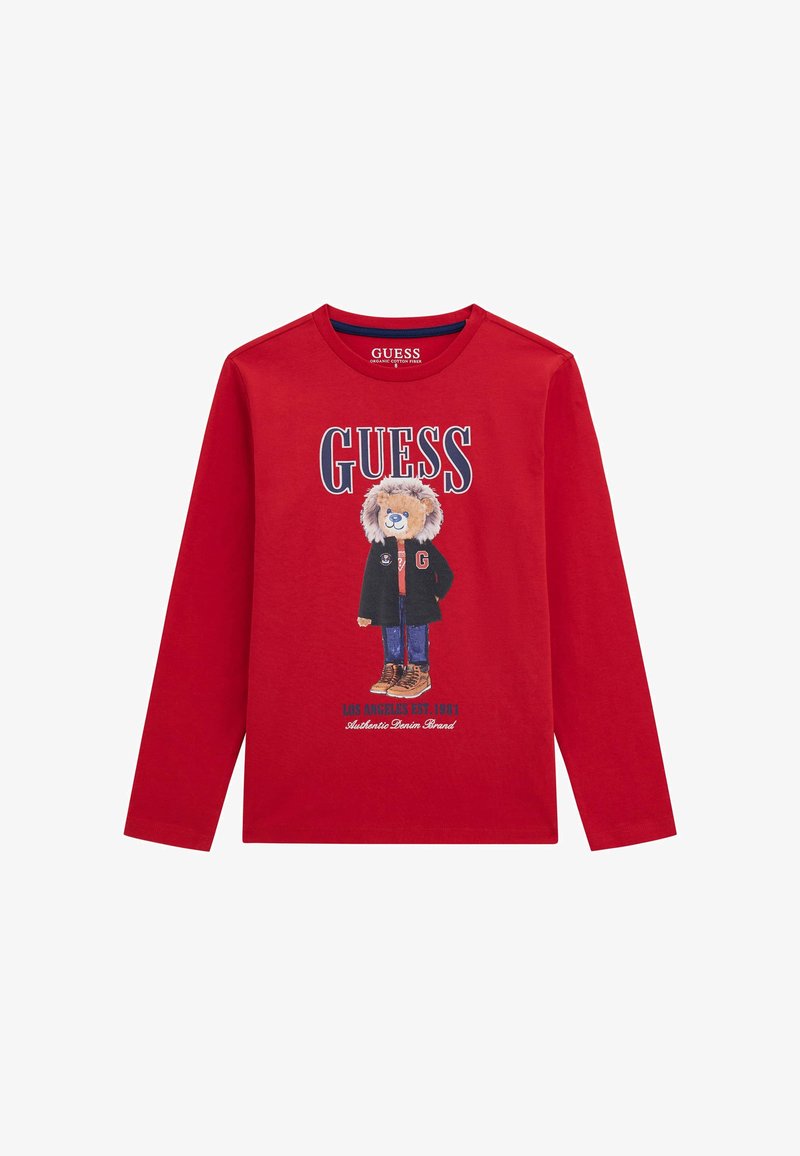 Pikkade varrukatega punane T-särk, millel on graafika lõvi karakterist mustas jope ja saapad. Ees on selgelt kirjutatud "GUESS".