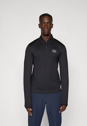 Svart langermet polo-skjorte med glidelås, med et strukturert stoff og en EA7-logo på brystet. Brukt med marineblå bukser.