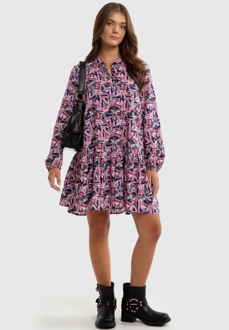 Long-sleeve dress with pink and purple leaf pattern, buttoned neckline, flared skirt, and black combat boots. Black handbag accent.
