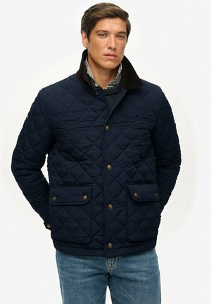 Chaqueta de navy acolchada con cuello de pana marrón, botones a presión y dos bolsillos frontales. Presenta un patrón de diamantes y un interior forrado.