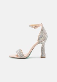 Sandalino beige con tacco alto e spesso, decorato con scintillanti strass, caratterizzato da una fascia alla caviglia e un design open-toe liscio.