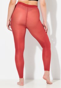 Rote, durchsichtige Leggings mit hohem Bund, taillierter Passform und glatter Textur, die einen nahtlosen Rücken und einen knöchellangen Schnitt präsentieren.